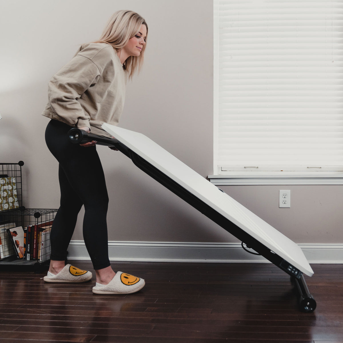 Standing desk with wheels being rolled across a floor on four casters